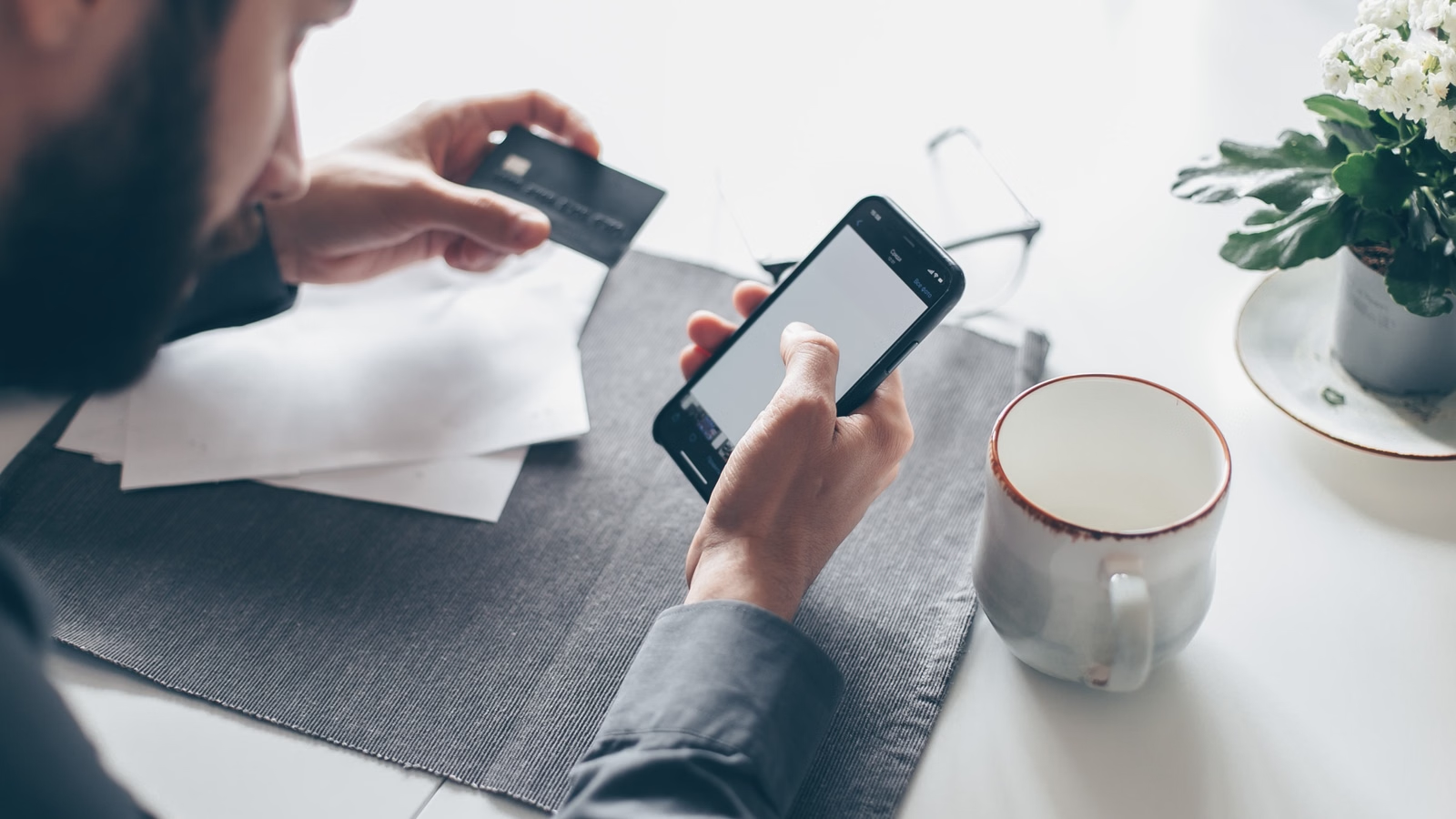 Person using phone and card for payment at a table