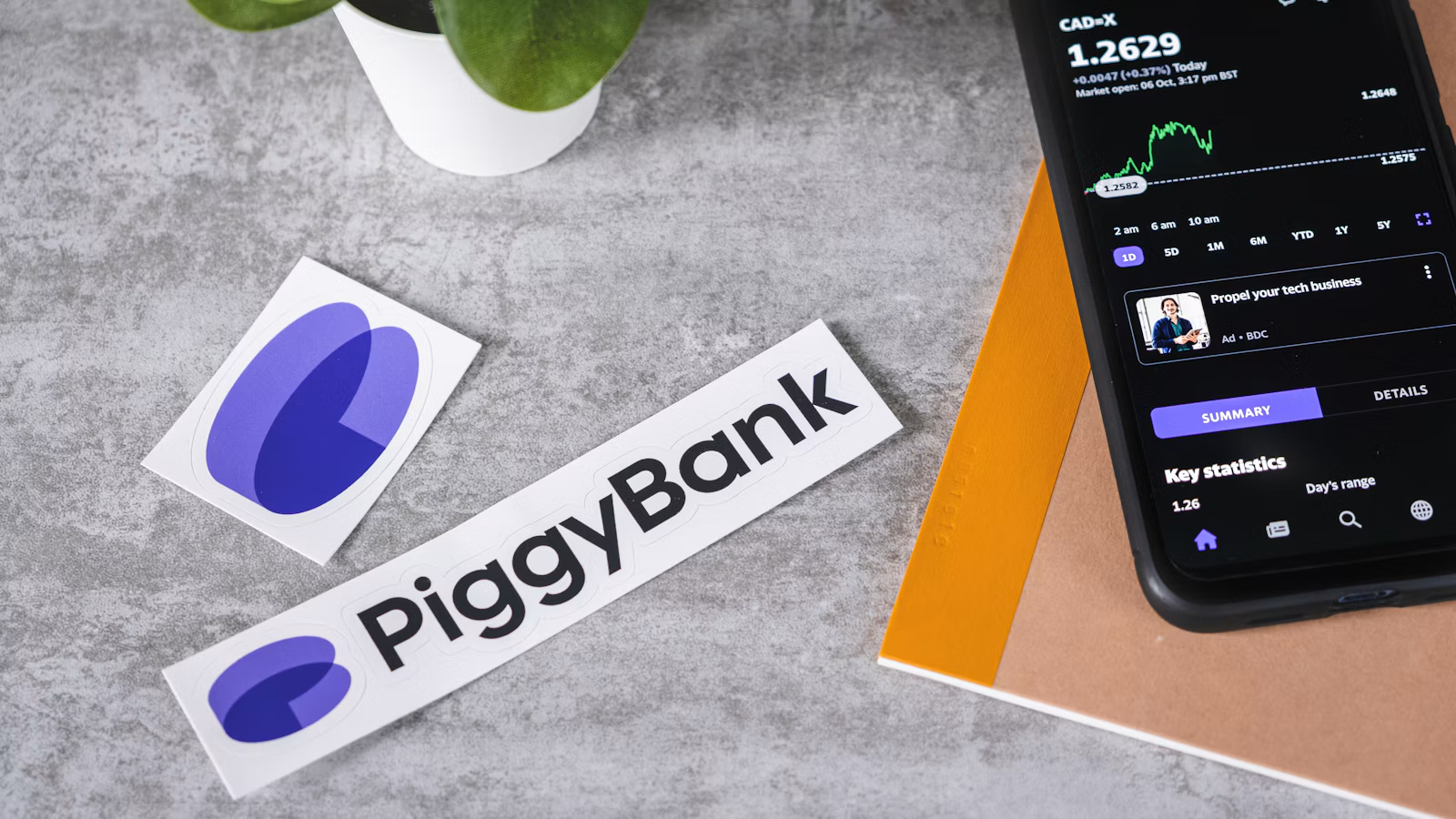 Financial information on a phone beside savings-themed stickers on a desk