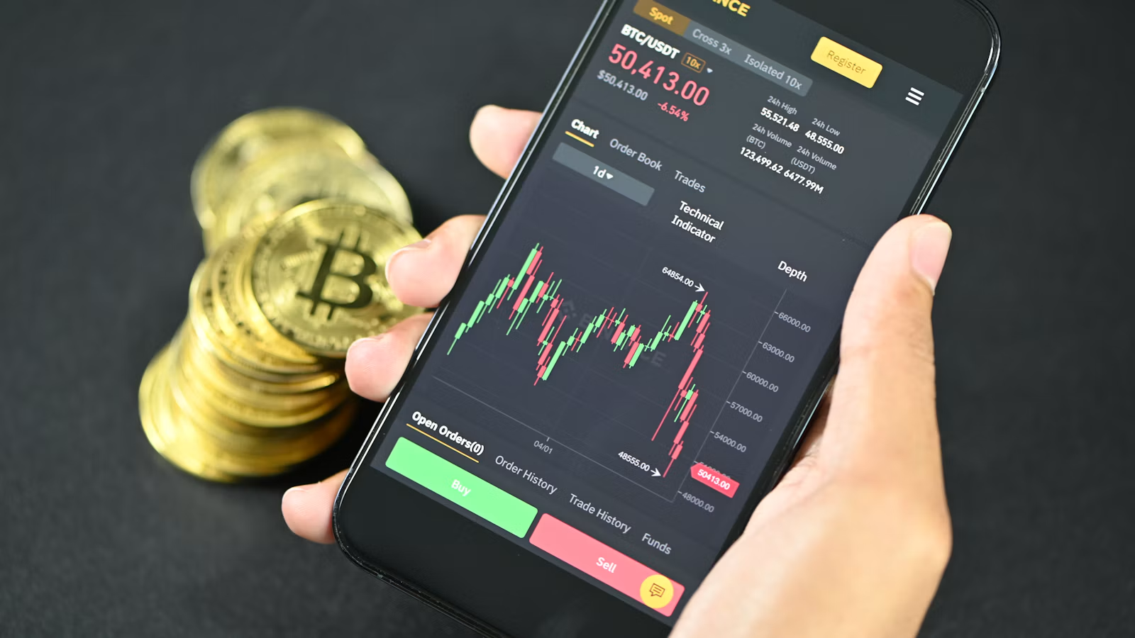 展示加密货币行情的手机与实体比特币纪念币