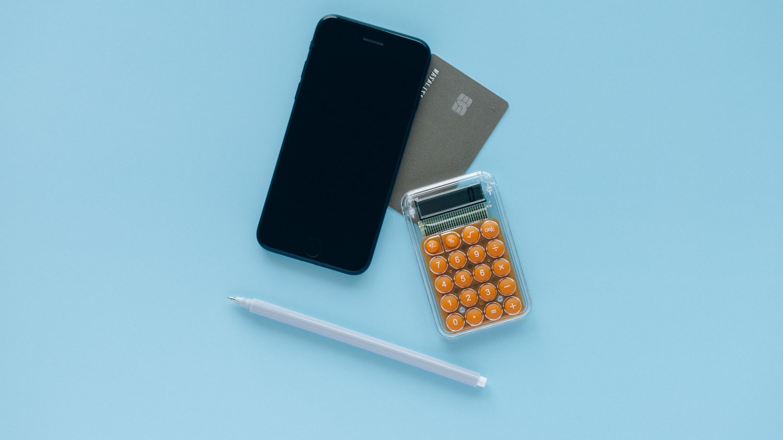 A phone, bank card, and calculator on a blue surface
