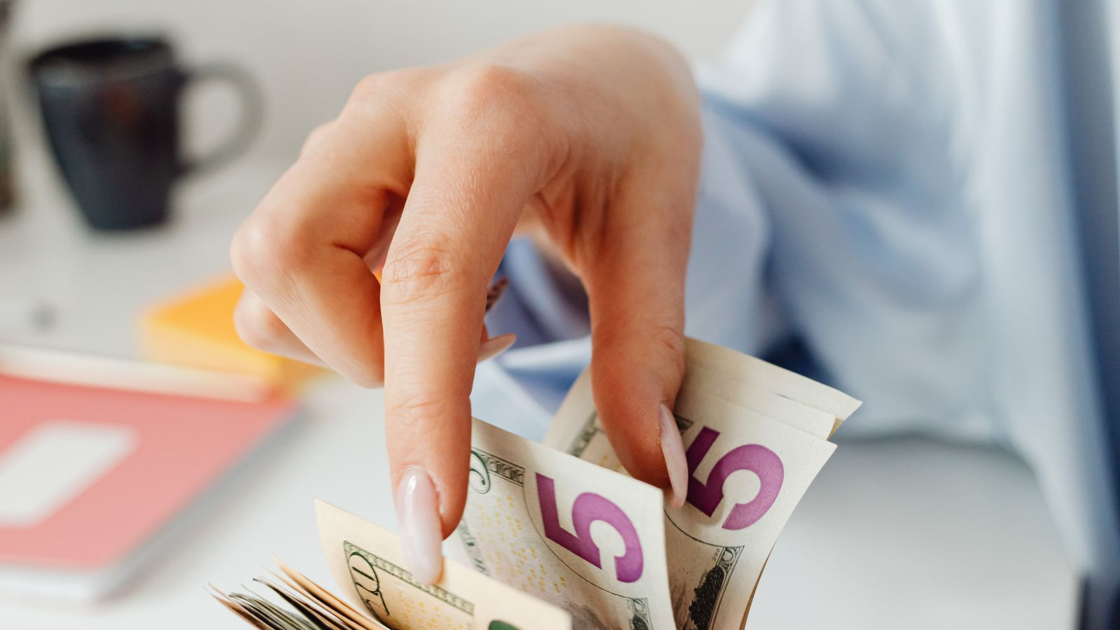 A person holding banknotes in different currencies, illustrating cash needs in international transfers