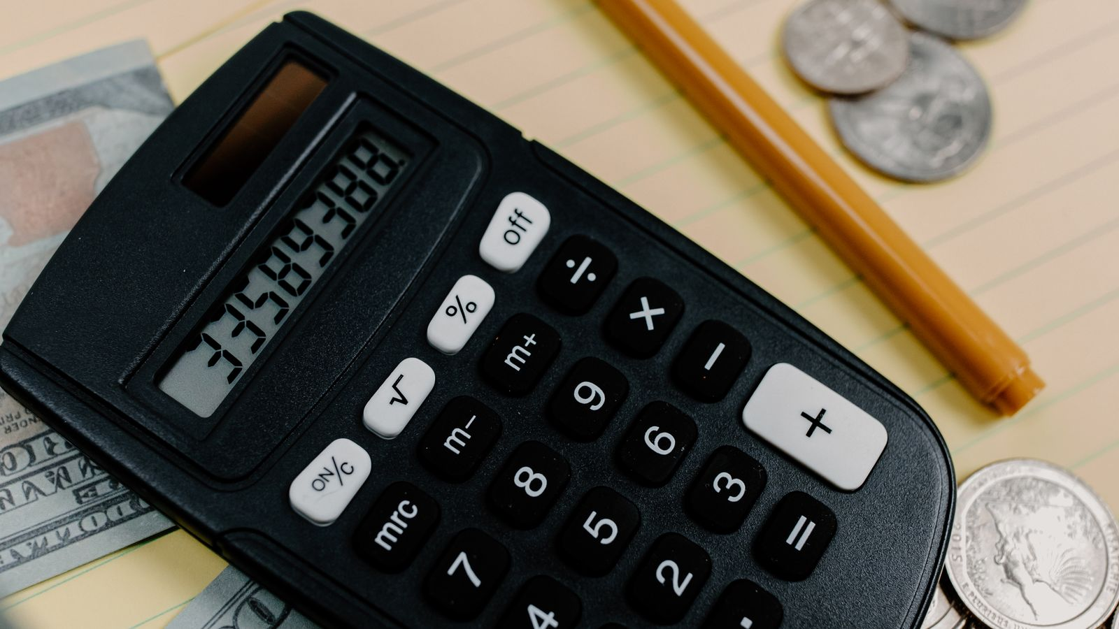 A calculator, banknotes, and a notepad for assessing international transfer costs