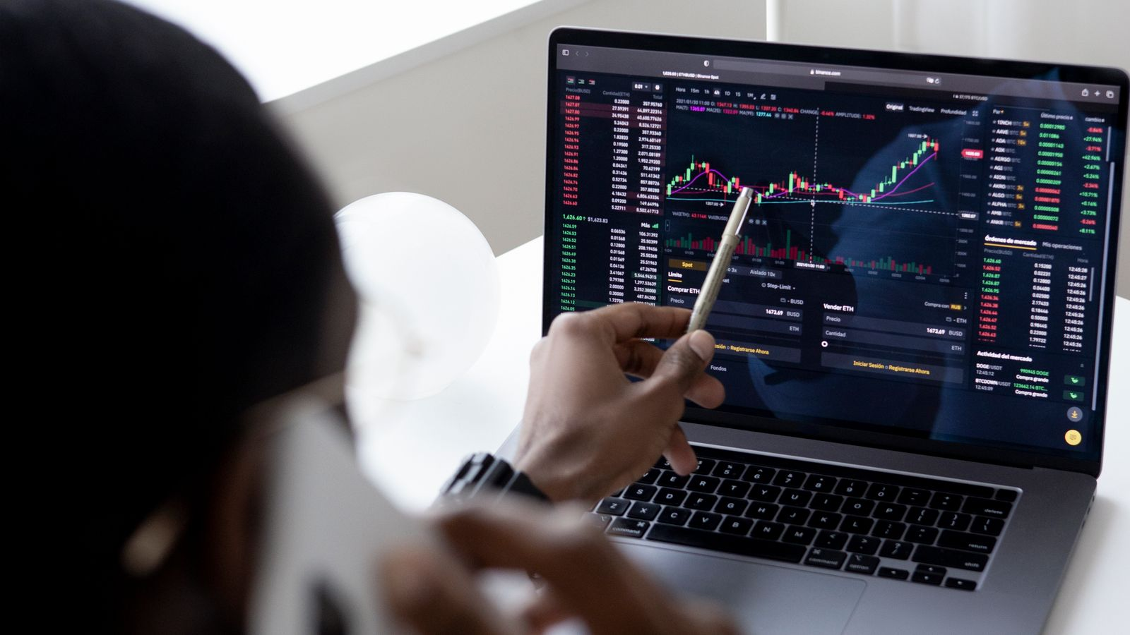 A user checks a trading interface on a laptop, illustrating the review of trading products and account conditions