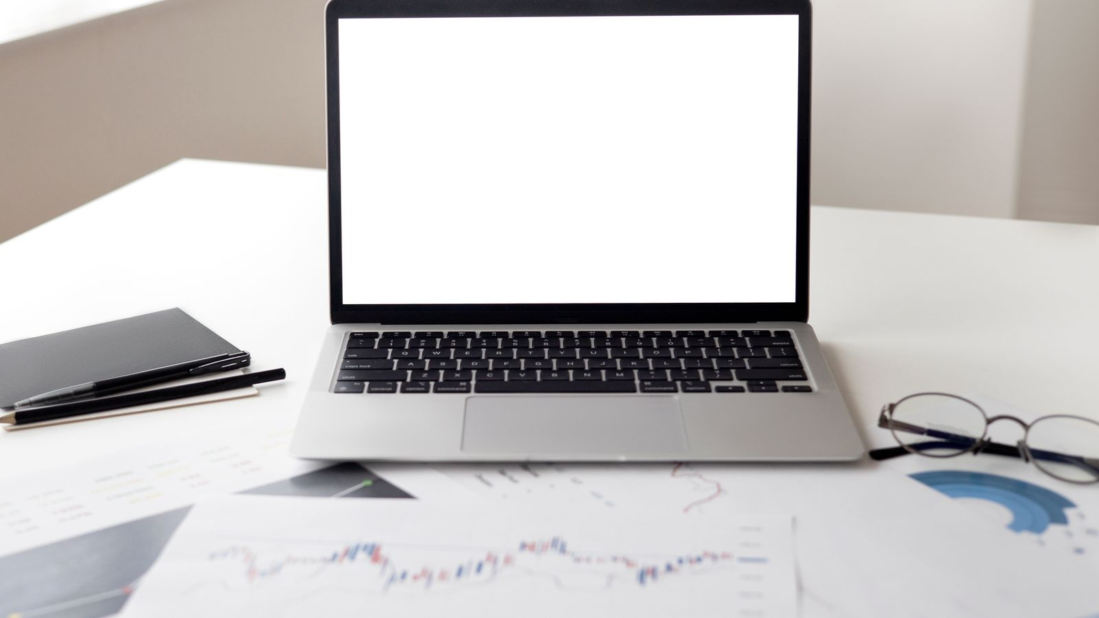 A laptop and printed market charts used to review investment tools and trading information