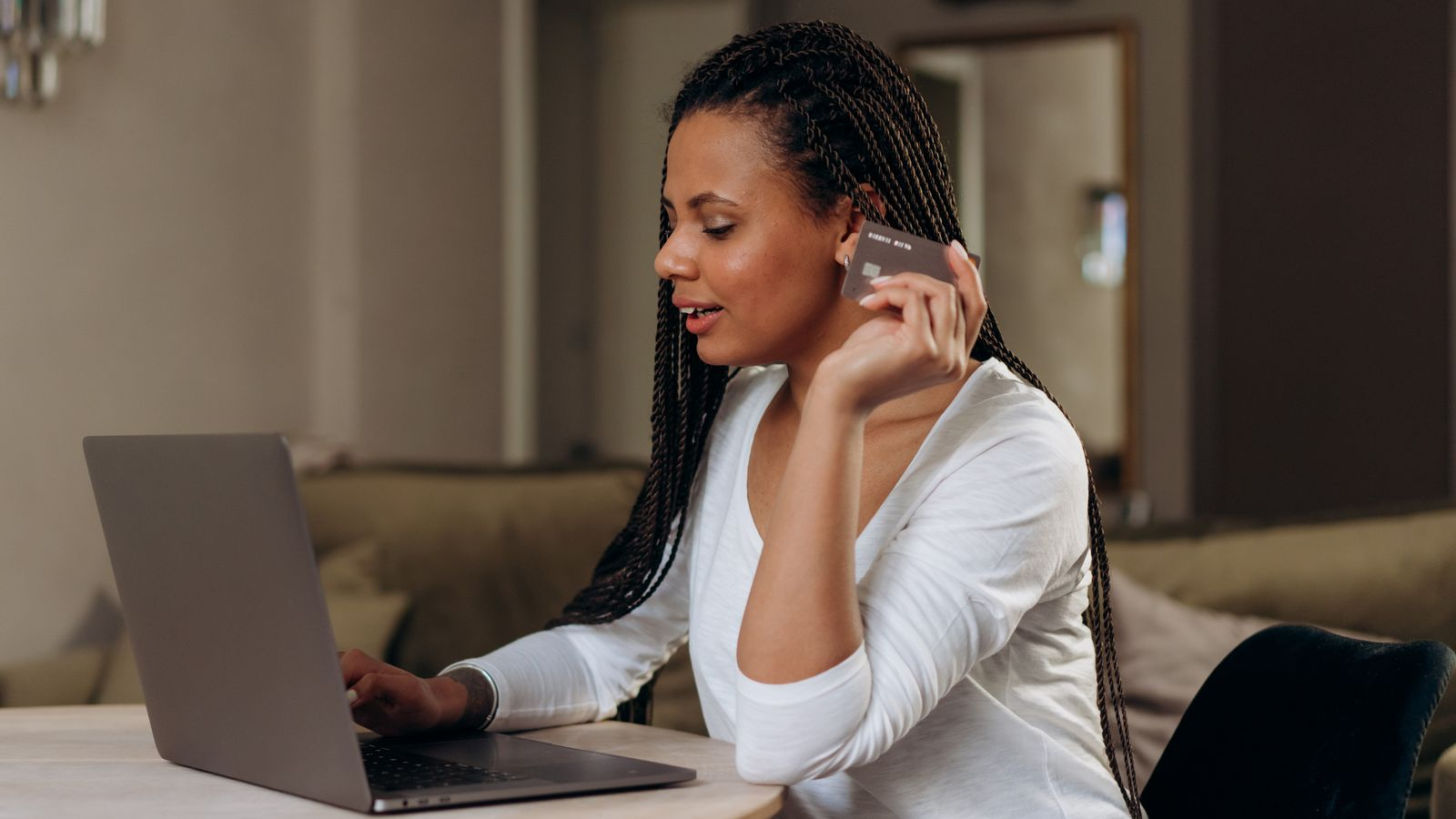 A user checking a payment card and online payment arrangements beside a computer