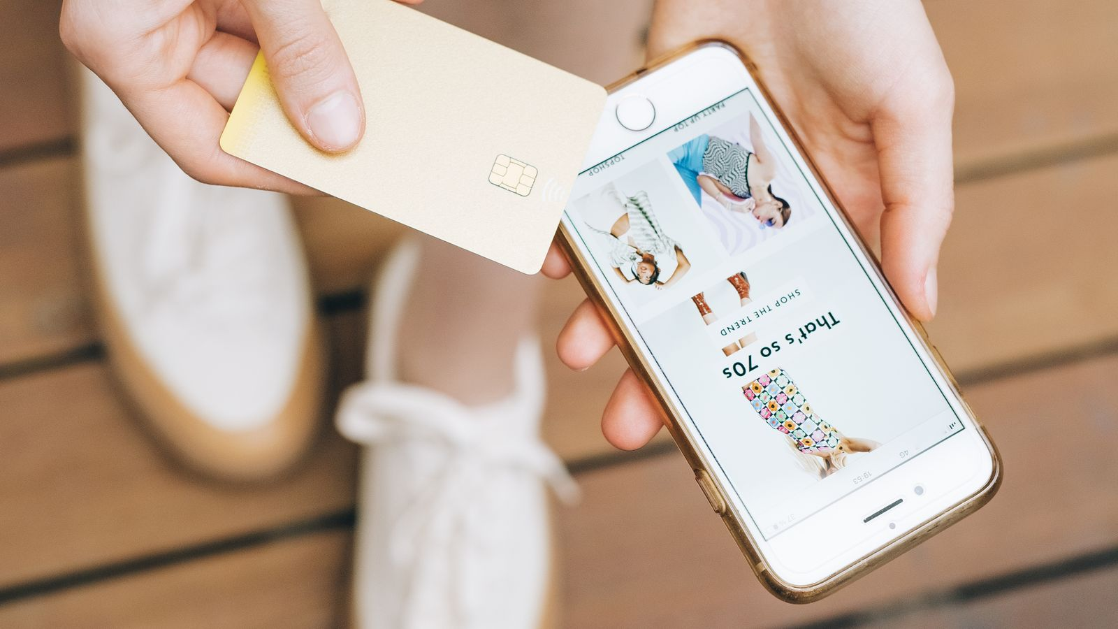 A user holding a bank card while browsing an online store on a phone, illustrating a digital payment use case